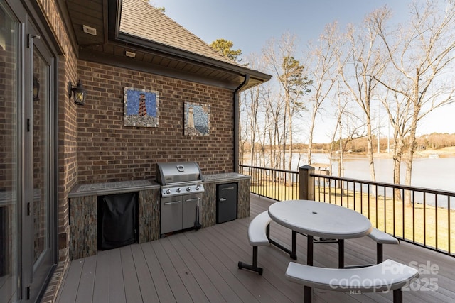 deck with area for grilling and a water view