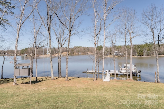 view of dock with a lawn and a water view