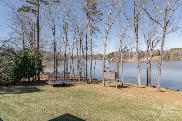 view of yard with a trampoline and a water view