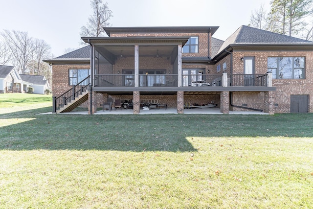 back of house with a yard, a patio area, brick siding, and stairs