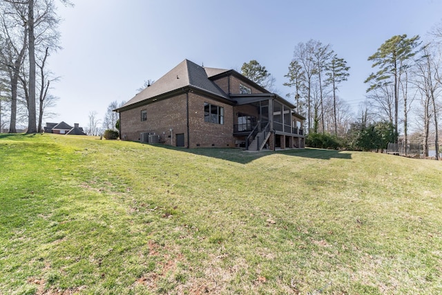 rear view of house featuring cooling unit, a lawn, and brick siding