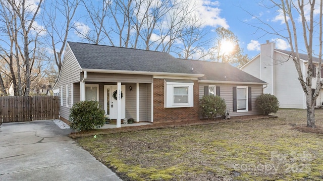 view of front of property with a shingled roof, fence, and brick siding