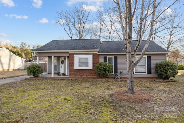 single story home featuring roof with shingles, a front yard, fence, and brick siding