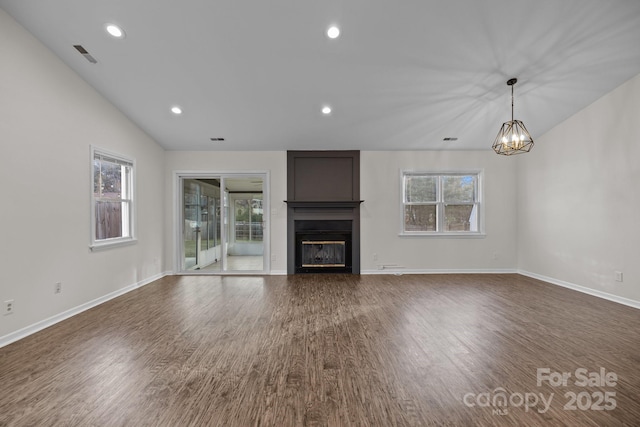 unfurnished living room with a large fireplace, dark wood-style floors, and a wealth of natural light