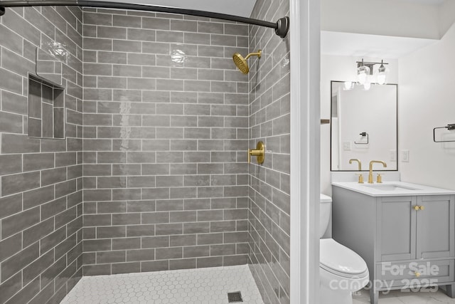 bathroom with a tile shower, vanity, and toilet