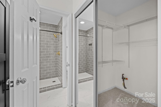 bathroom featuring a walk in closet and tiled shower