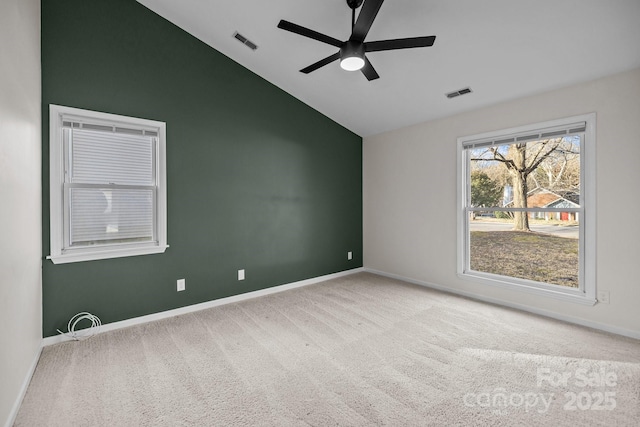 carpeted spare room with a ceiling fan, visible vents, vaulted ceiling, and baseboards