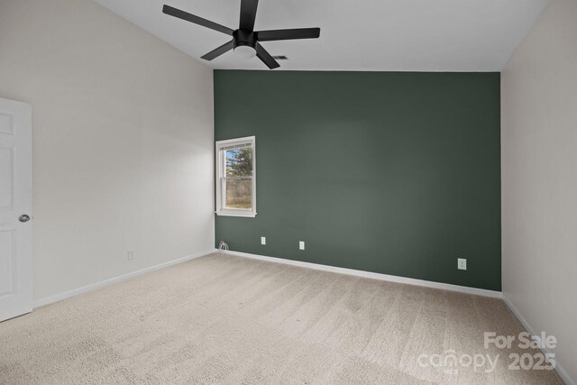 carpeted empty room with vaulted ceiling, ceiling fan, and baseboards