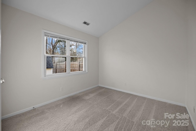 carpeted empty room with vaulted ceiling, visible vents, and baseboards