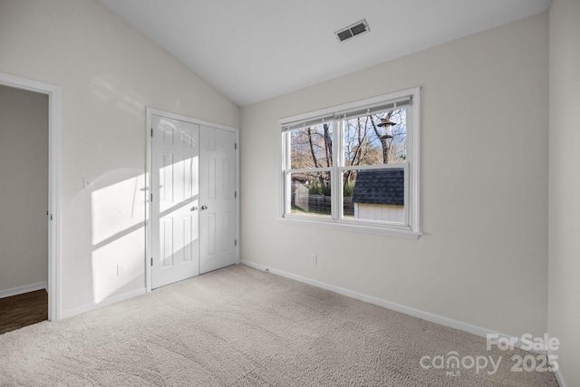 unfurnished bedroom with visible vents, baseboards, vaulted ceiling, carpet floors, and a closet