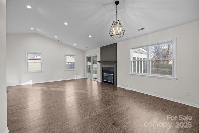 unfurnished living room with a large fireplace, vaulted ceiling, wood finished floors, and visible vents