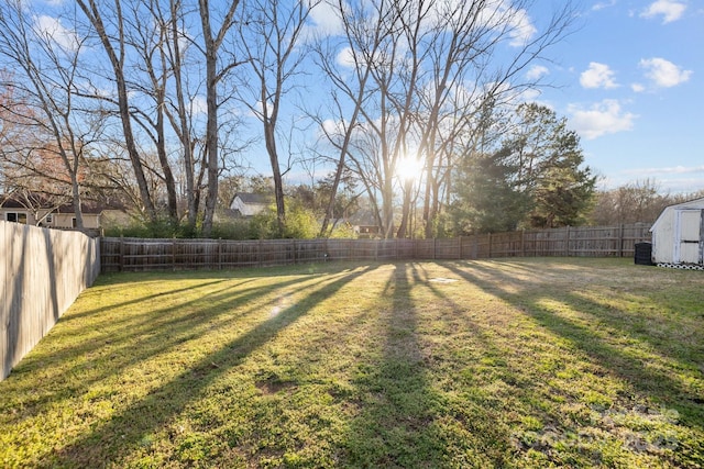 view of yard featuring an outbuilding, a storage shed, and a fenced backyard