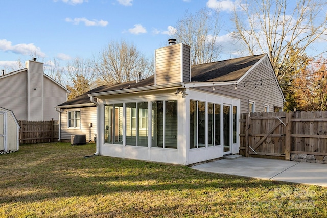 back of house featuring a lawn, a sunroom, a gate, a patio area, and fence