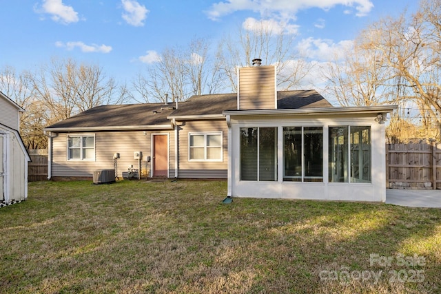 rear view of house featuring cooling unit, fence, a chimney, and a lawn