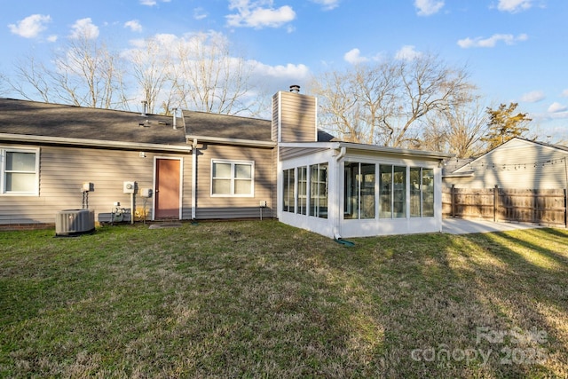 back of property with a yard, a sunroom, fence, and a chimney