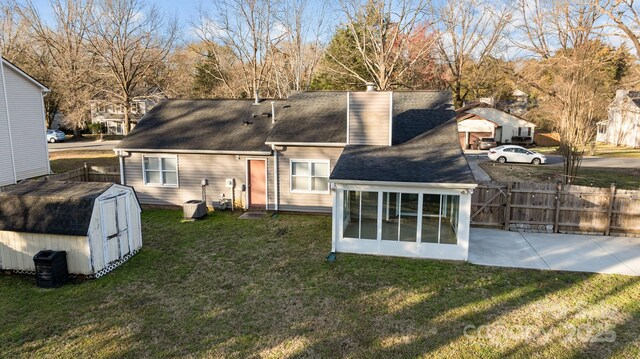 rear view of property featuring a sunroom, a gate, fence, and a lawn