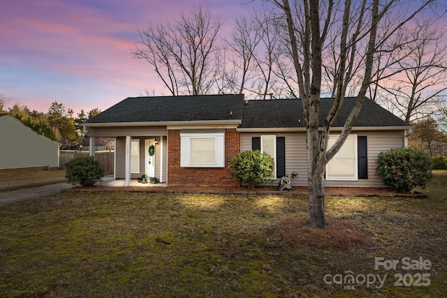 single story home with a shingled roof, fence, a lawn, and brick siding