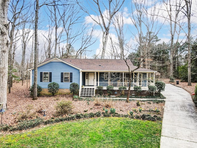 ranch-style house featuring a porch, driveway, a shingled roof, and a front lawn