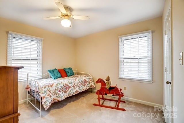 carpeted bedroom featuring multiple windows, baseboards, and a ceiling fan