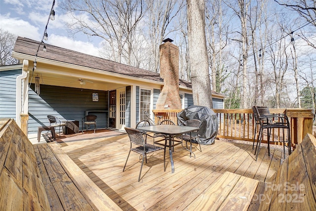 deck with outdoor dining space and a ceiling fan