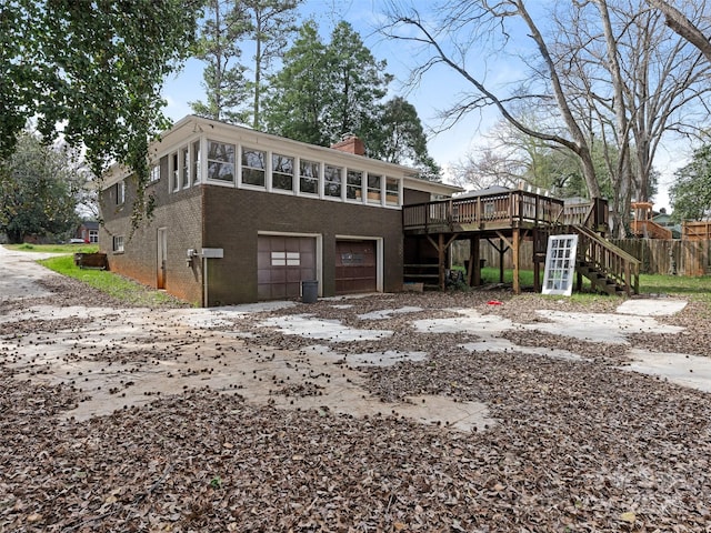 view of front of house with a chimney, an attached garage, stairs, a wooden deck, and brick siding