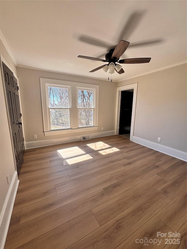 unfurnished bedroom featuring dark wood-style floors, baseboards, visible vents, and crown molding