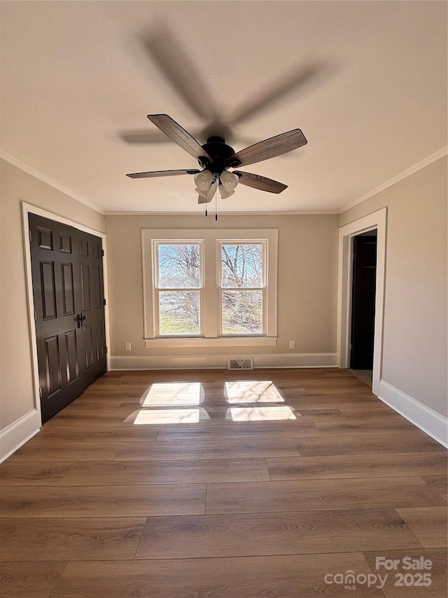 interior space with visible vents, baseboards, ceiling fan, dark wood-style flooring, and crown molding