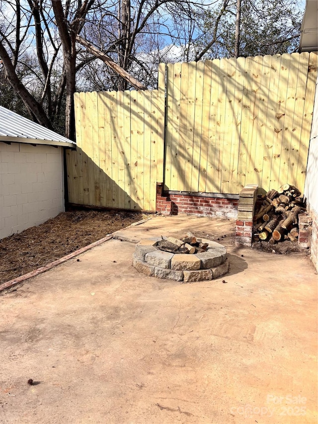 view of patio featuring an outdoor fire pit and fence