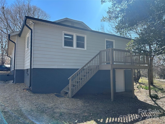 rear view of house with brick siding, a deck, and stairs