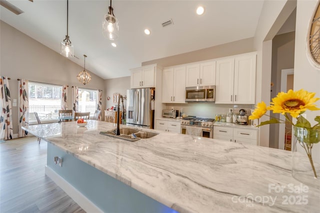 kitchen featuring light stone counters, stainless steel appliances, a sink, white cabinetry, and light wood-type flooring