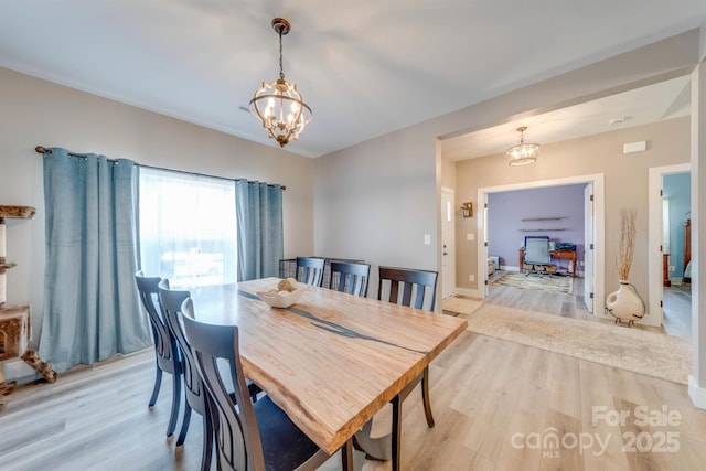 dining space featuring a chandelier, baseboards, and light wood finished floors