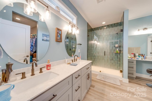 bathroom featuring a stall shower, a sink, and wood finished floors