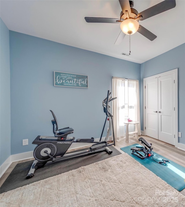 exercise room featuring visible vents, ceiling fan, baseboards, and wood finished floors