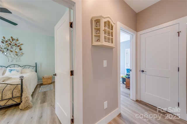 corridor featuring light wood-style flooring and baseboards