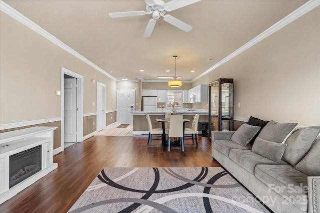 living room with ceiling fan, recessed lighting, a fireplace, wood finished floors, and crown molding