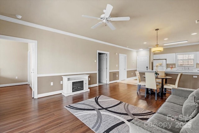 living area with dark wood-style floors, a glass covered fireplace, and crown molding