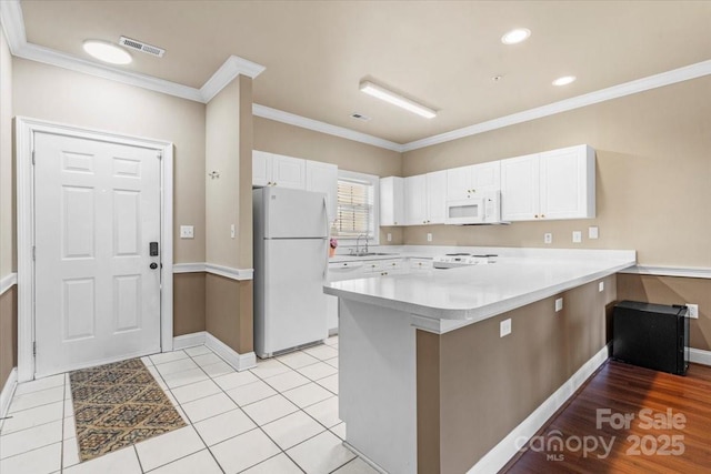 kitchen with white appliances, visible vents, white cabinets, light countertops, and a sink