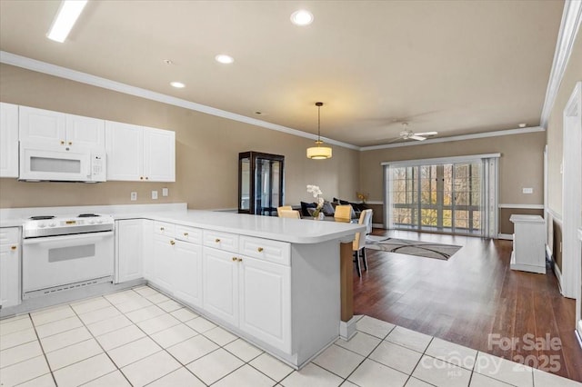kitchen featuring white appliances, white cabinets, open floor plan, a peninsula, and light countertops