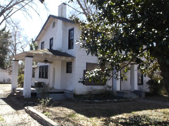 view of front of home featuring a ceiling fan, a chimney, and central AC unit