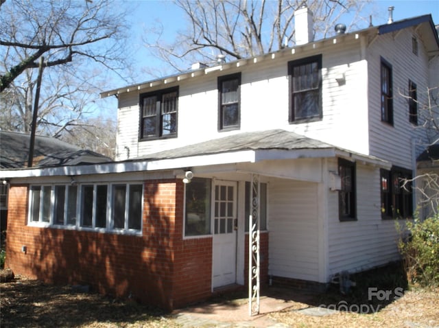 view of front of house featuring a chimney and brick siding