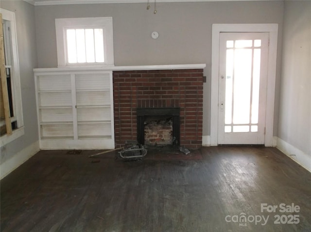 unfurnished living room with a brick fireplace, baseboards, and wood finished floors