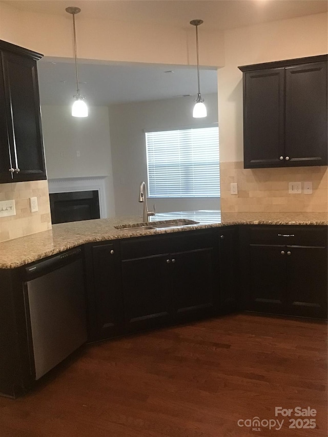 kitchen with dark wood finished floors, dishwasher, light stone counters, a fireplace, and a sink