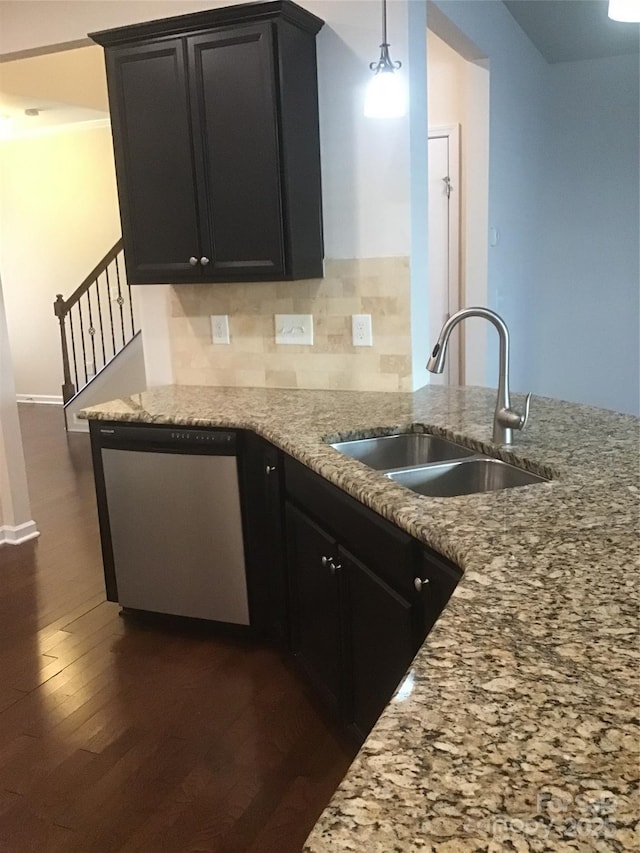 kitchen with light stone counters, dark wood finished floors, a sink, decorative backsplash, and dishwasher