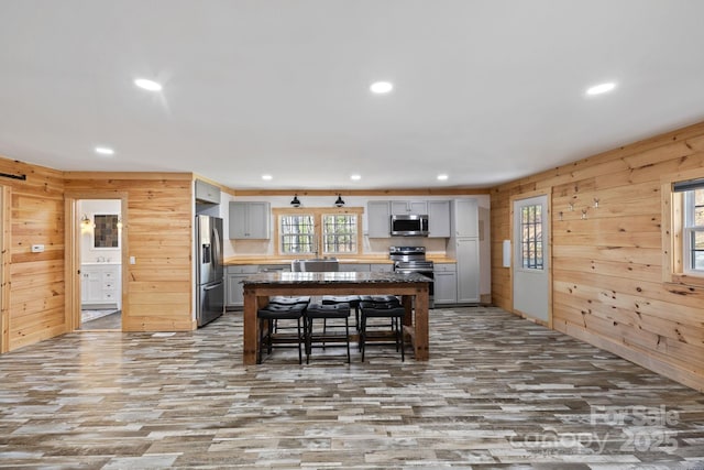 kitchen with a breakfast bar, stainless steel appliances, recessed lighting, gray cabinetry, and a kitchen island