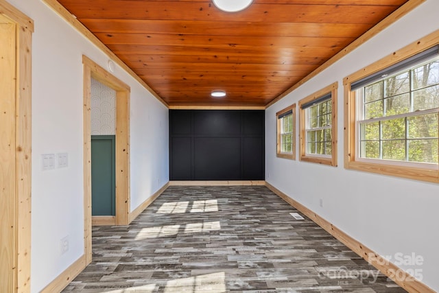 empty room with wood ceiling, baseboards, and wood finished floors