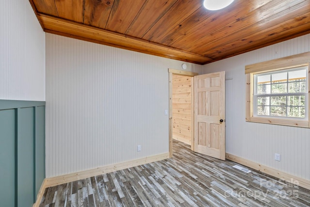 spare room featuring wood finished floors, wood ceiling, and baseboards