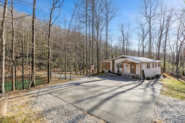 view of home's exterior with aphalt driveway and a wooded view