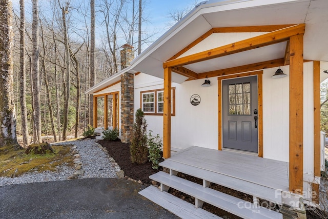 doorway to property featuring a chimney and stucco siding