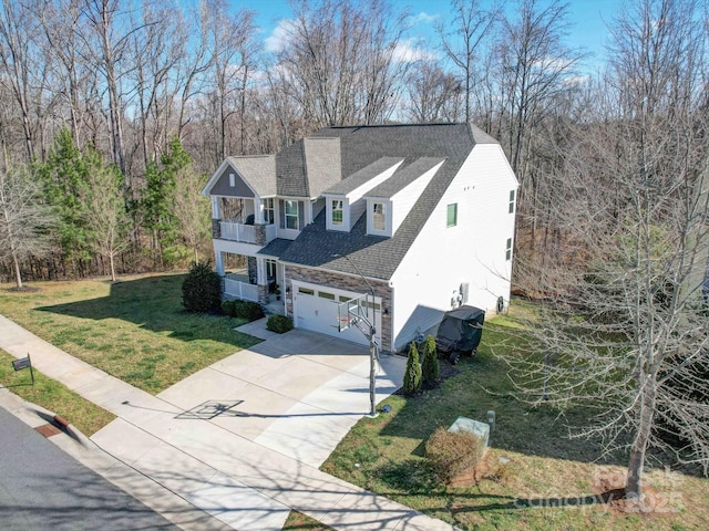 view of front facade featuring a shingled roof, a balcony, a garage, driveway, and a front lawn