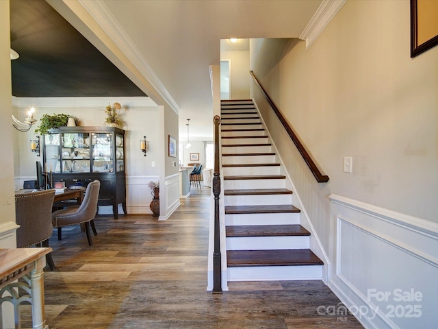 stairs featuring ornamental molding, a wainscoted wall, a decorative wall, and wood finished floors